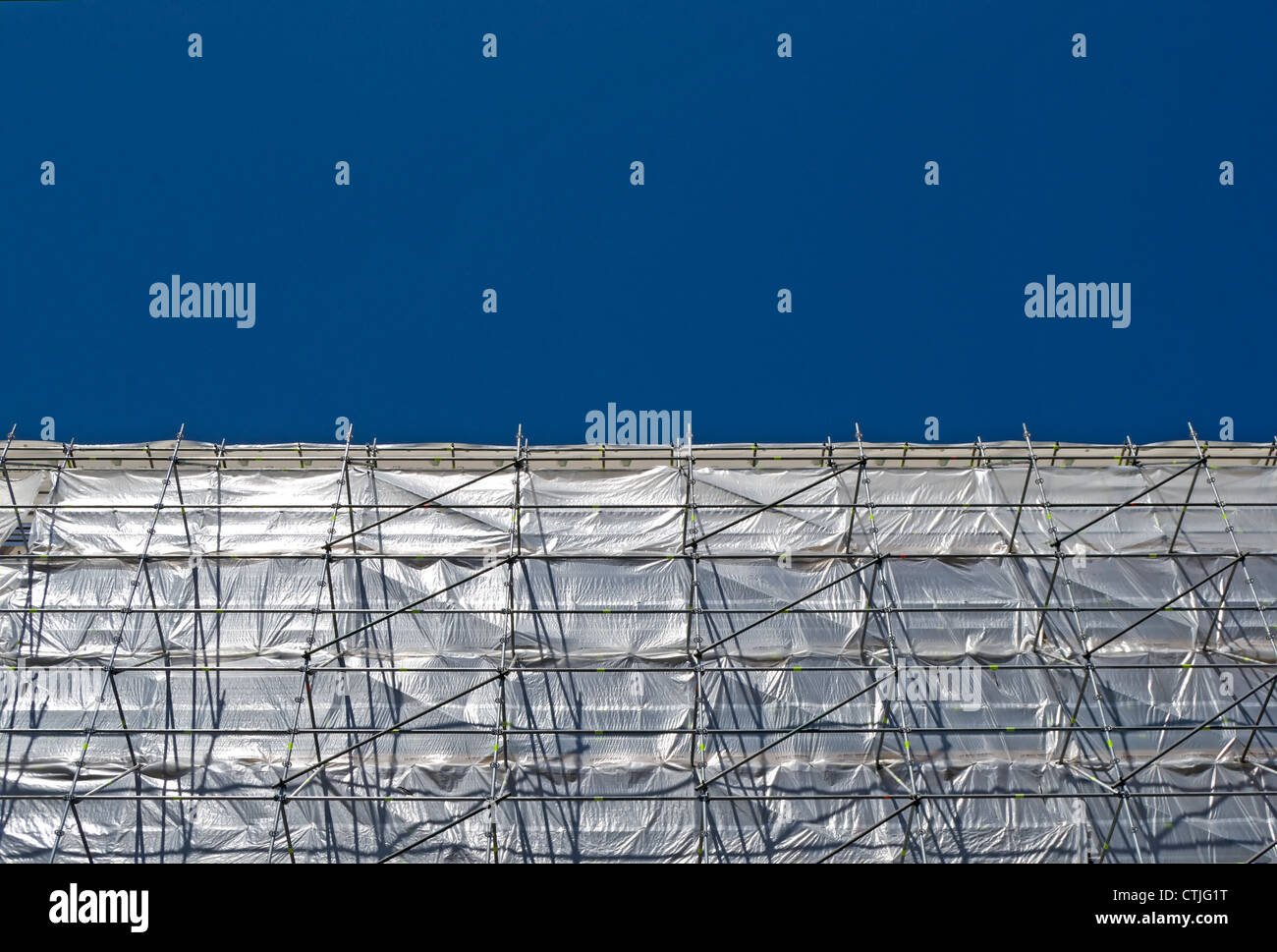 seen against a blue sky, flame retardant sheets draped around scaffolding at a construction site in west london Stock Photo
