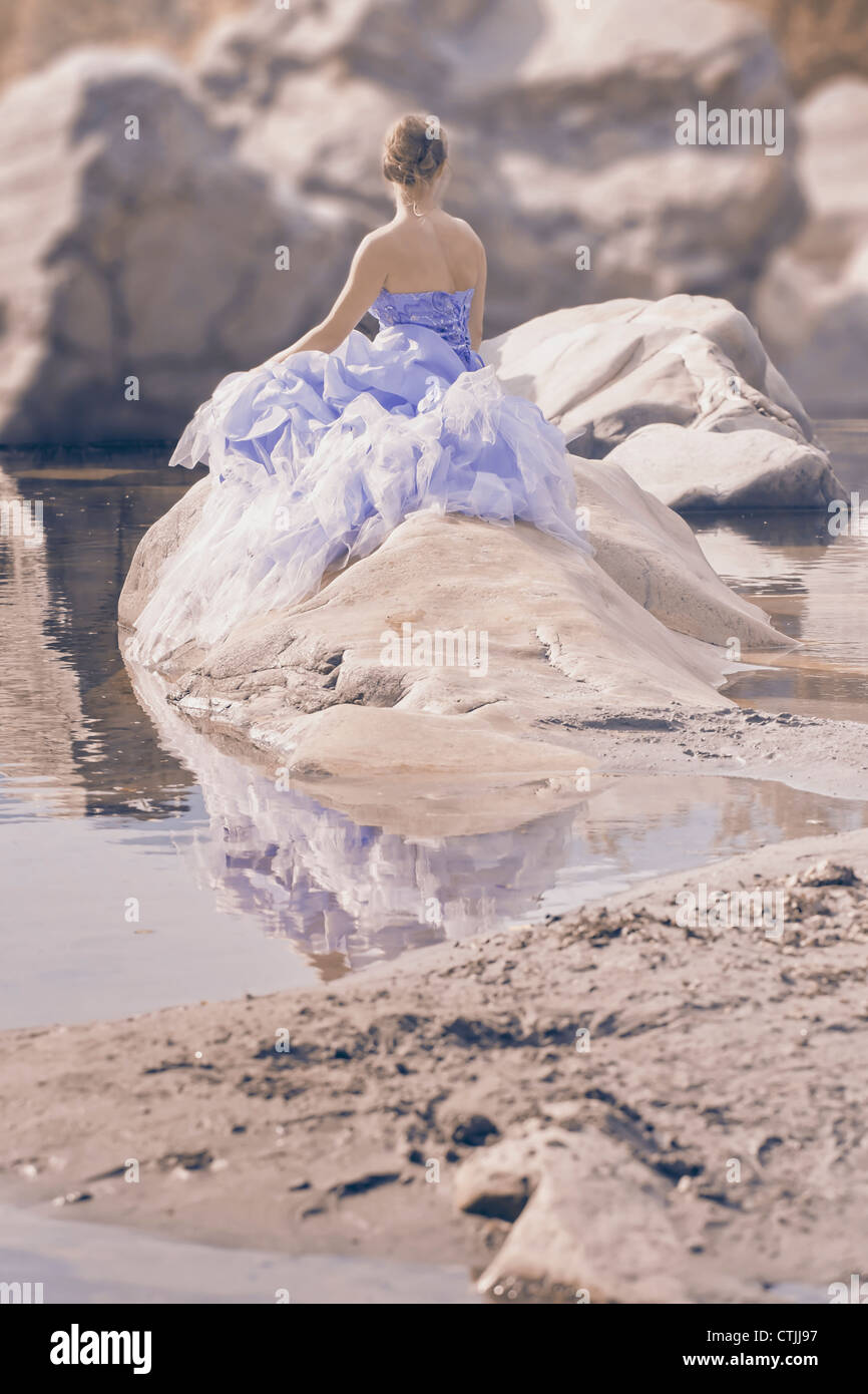 a woman in evening dress sitting on a rock in water Stock Photo - Alamy