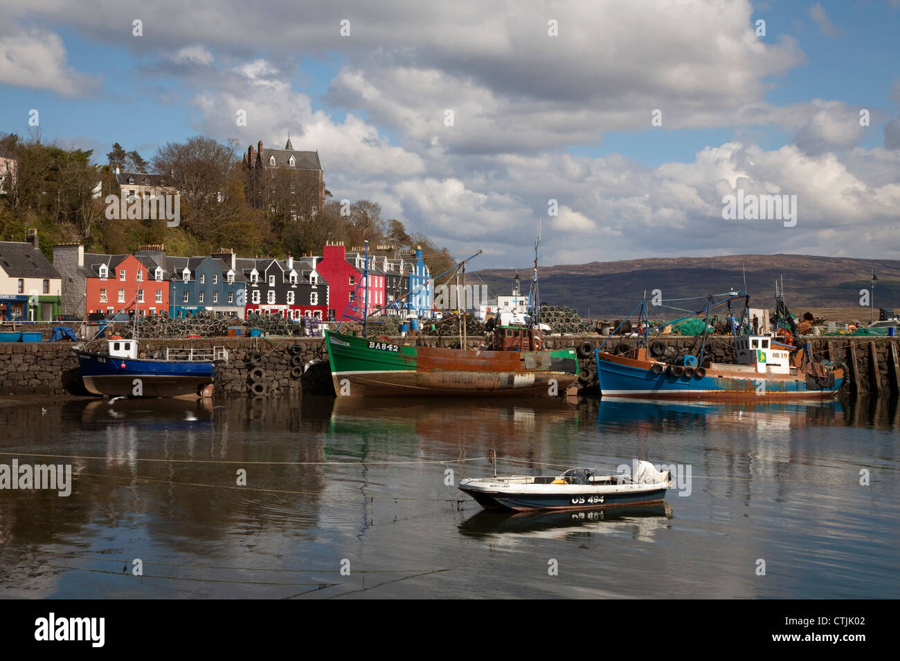 Fishing boats at the pier in the harbour at Tobermory on the Isle of Mull in Scotland with famous bright colourful buildings Stock Photo
