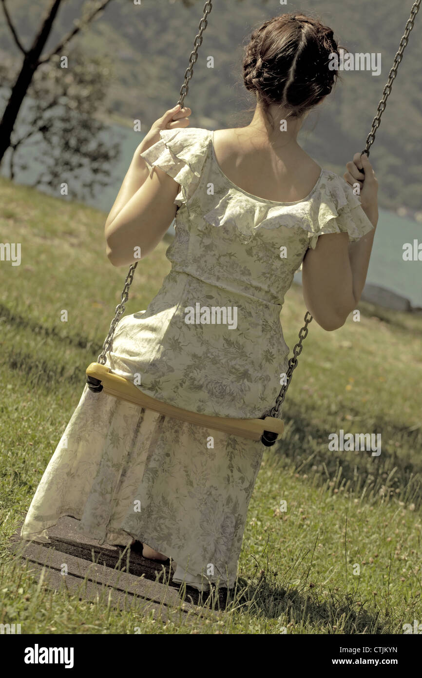 a woman in a floral dress swinging on a swing Stock Photo - Alamy