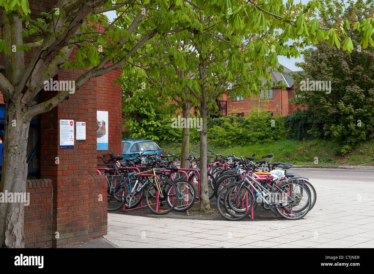Bicycles parked securely in a parking area outside a railway station in England. Stock Photo