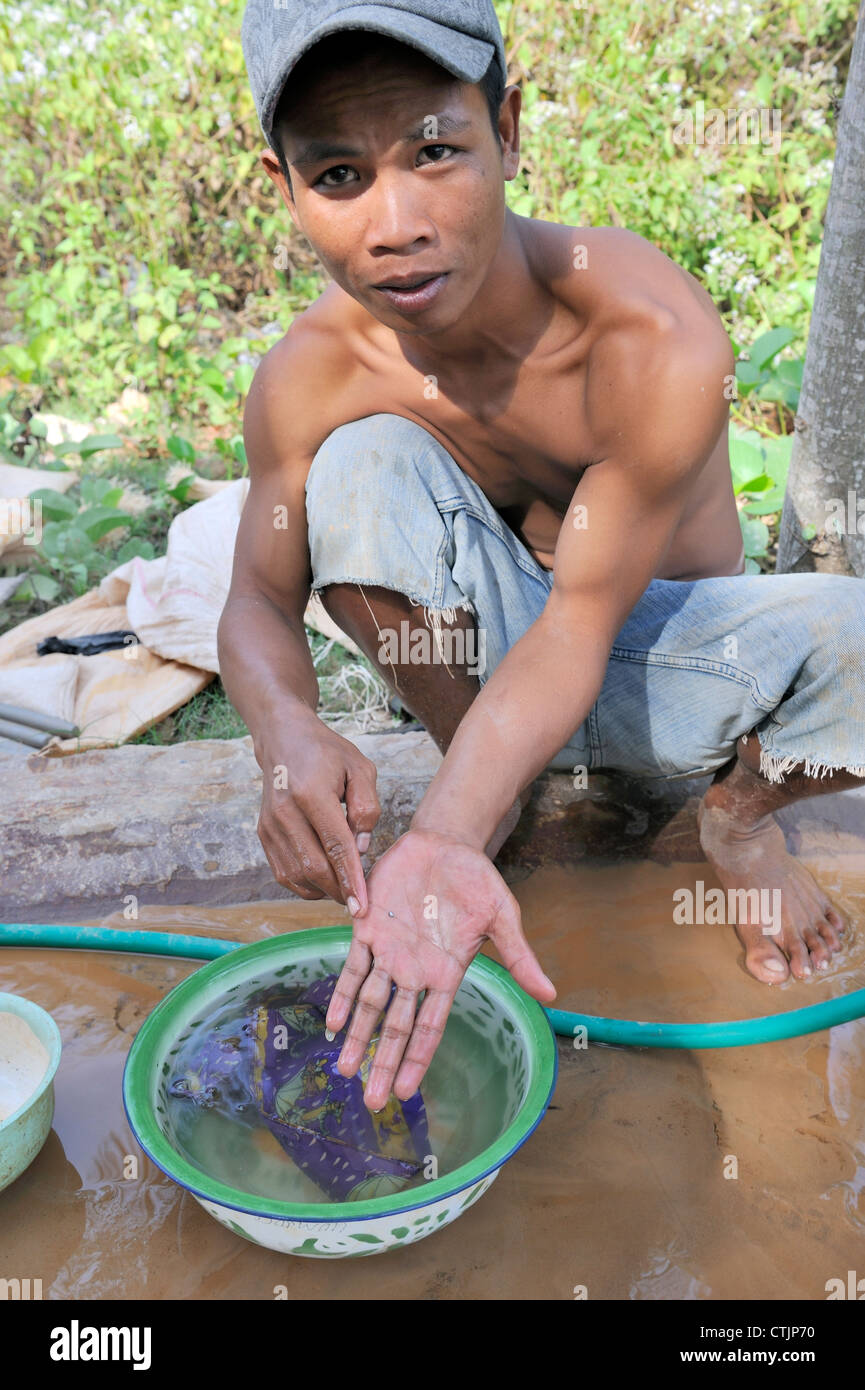 Asian gold miner showing a speck of gold he has found Stock Photo