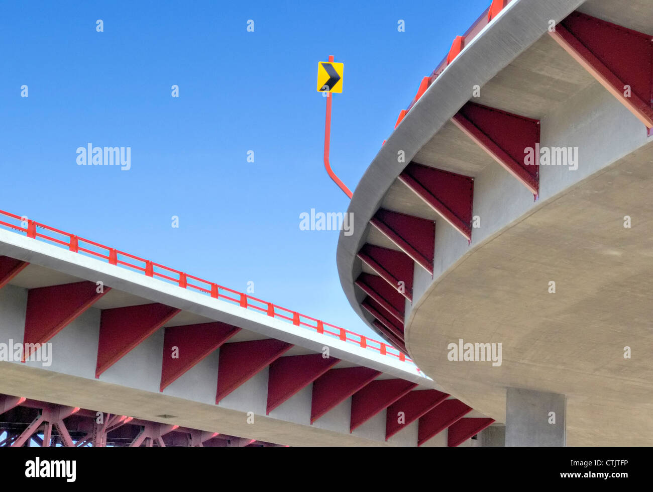 Modern curved concrete freeway ramp with distinctive red support ...