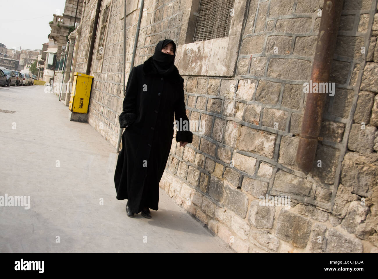 Muslim woman walking along the street, in Aleppo, Syria. Stock Photo