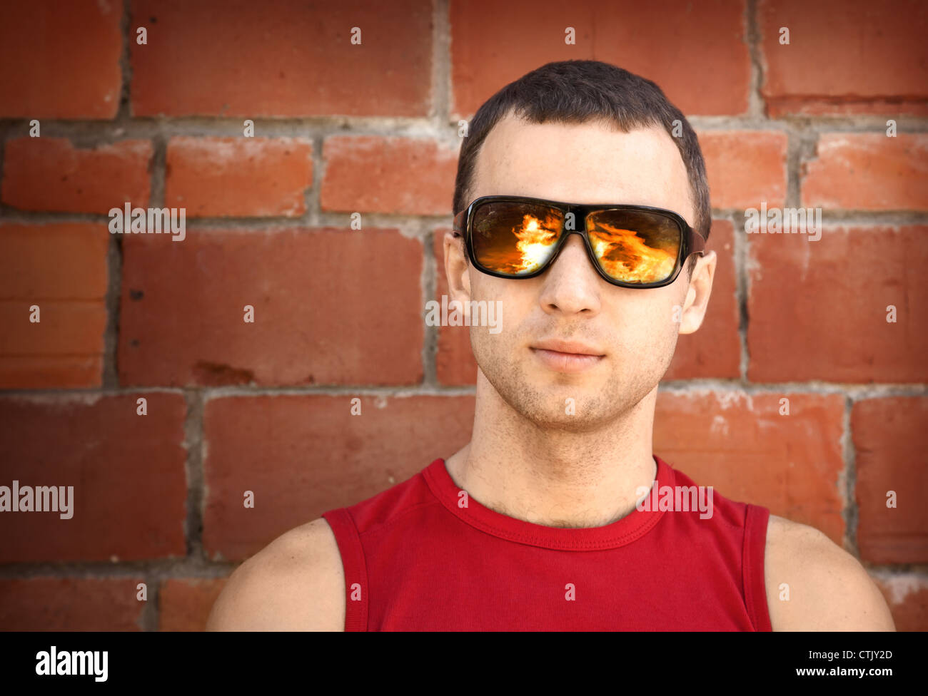 Closeup portrait of young man in black sunglasses with reflected fire Stock Photo