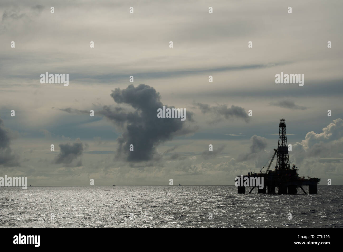 Silhouette of an Offshore floating oil drilling rig platform.  Clouds in dusk day. Stock Photo