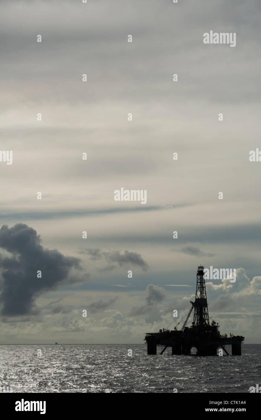 Silhouette of an Offshore floating oil drilling rig platform.  Clouds in dusk day. Stock Photo