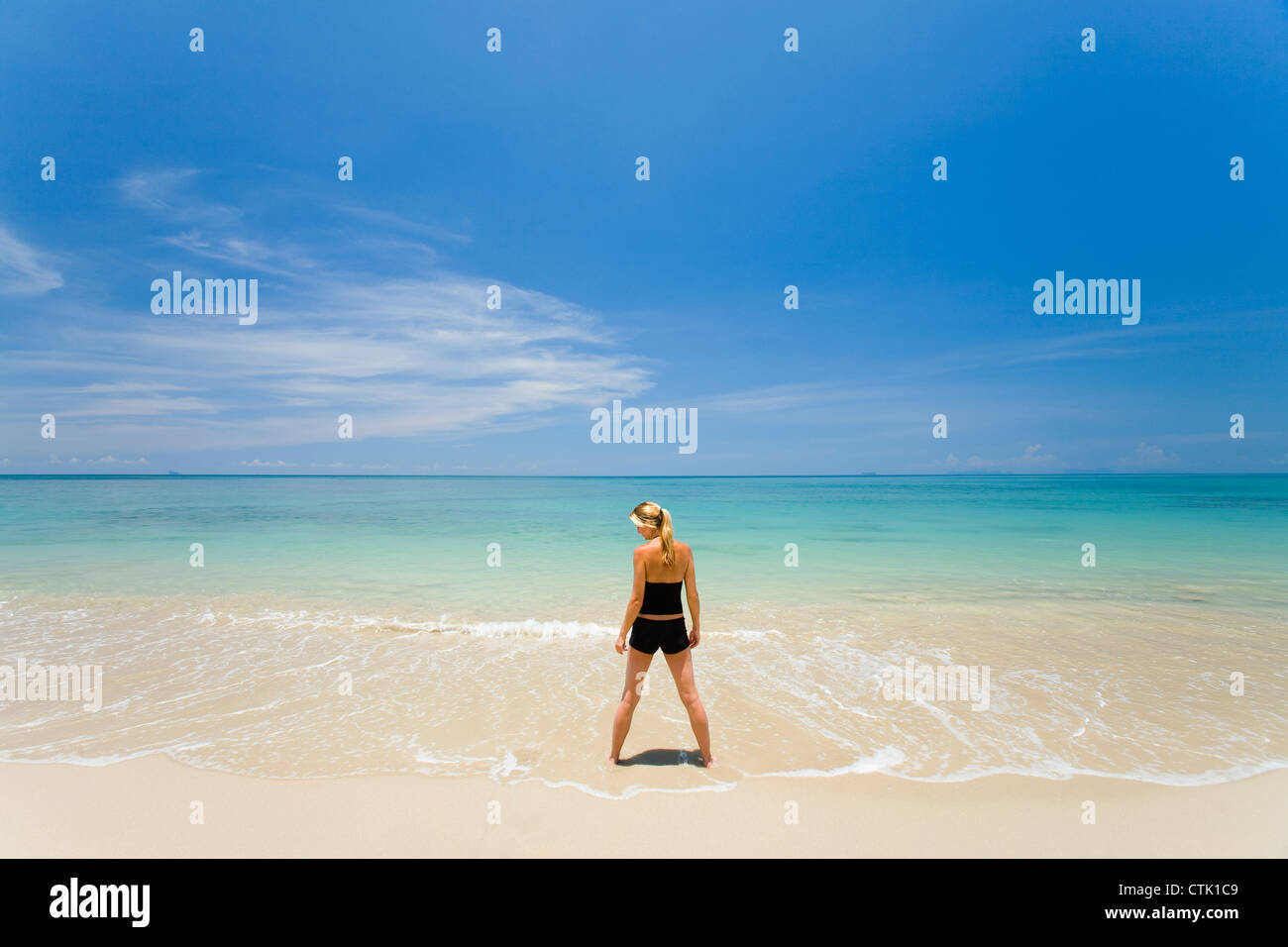 A Woman Tourist Stands In The Shallow Clear Waters Of A Tropical Island; Koh Lanta,Thailand Stock Photo