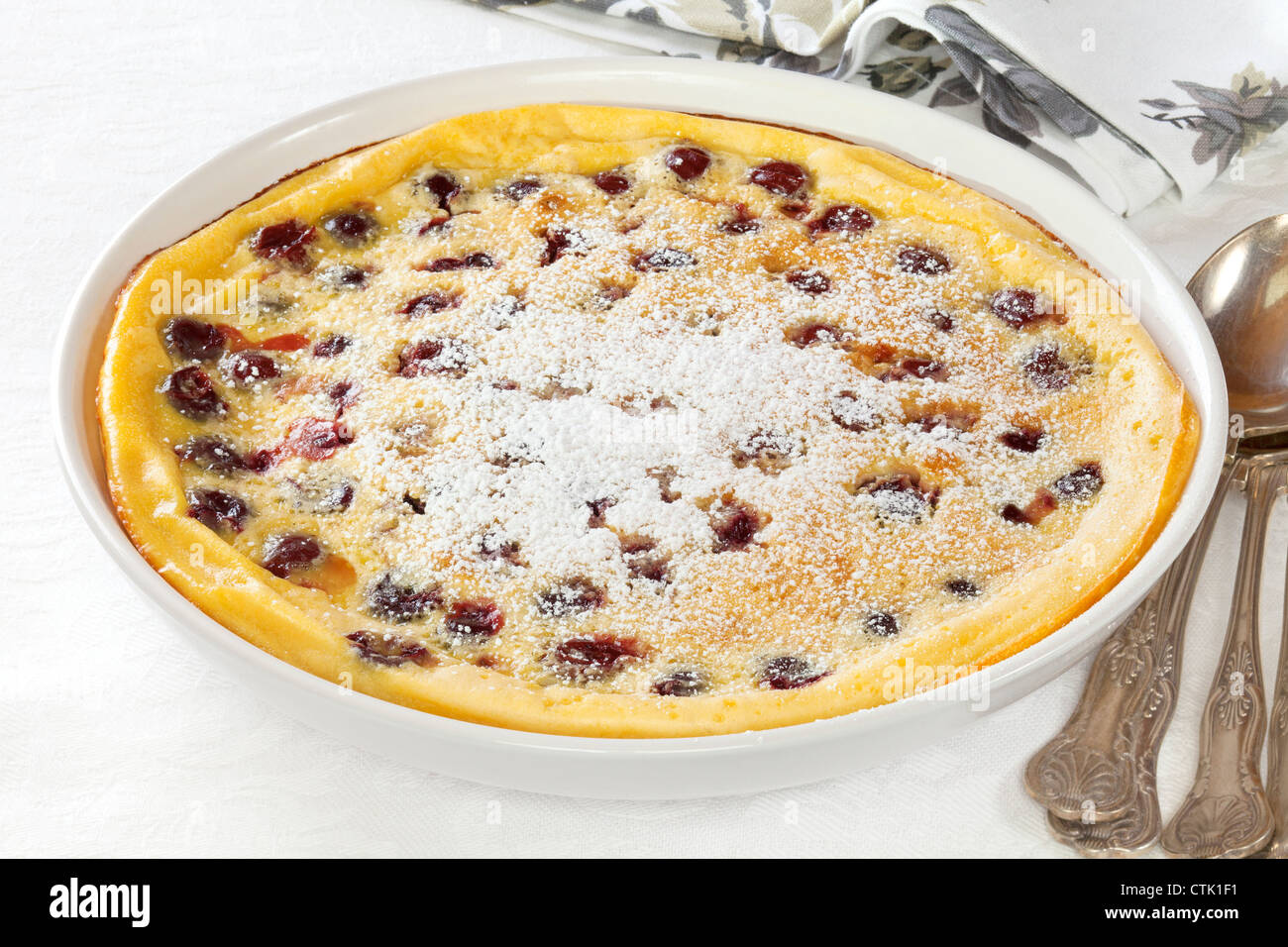 Popular French dessert Cherry Clafoutis, a baked batter pudding with morello cherries, sprinkled with icing sugar. Stock Photo