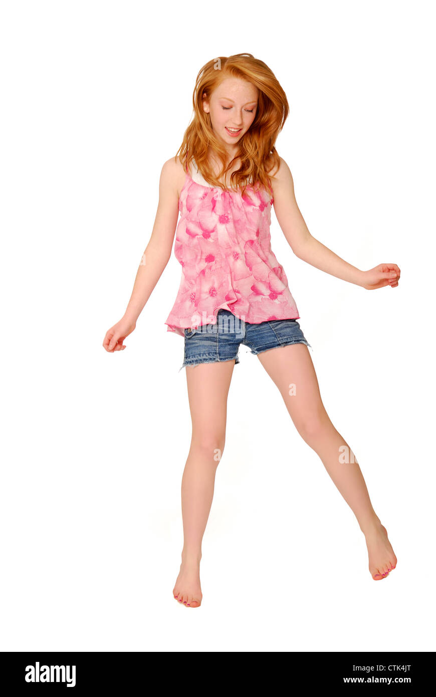 Pretty fourteen year old girl wearing pink flowered shirt and cutoff bluejean shorts, jumping or bouncing. Stock Photo