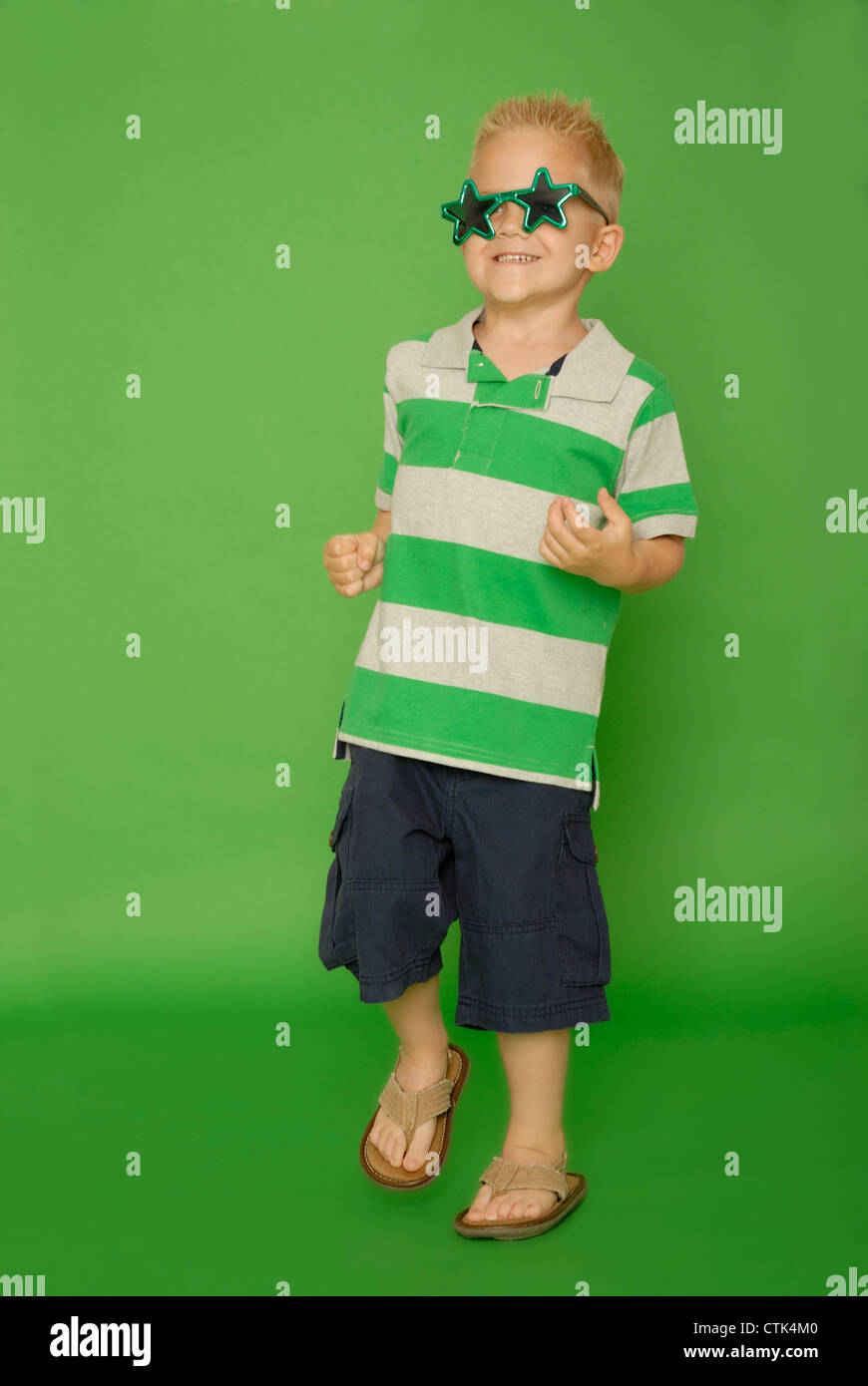 Five year old boy wearing star glasses and dancing or playing air guitar. Stock Photo