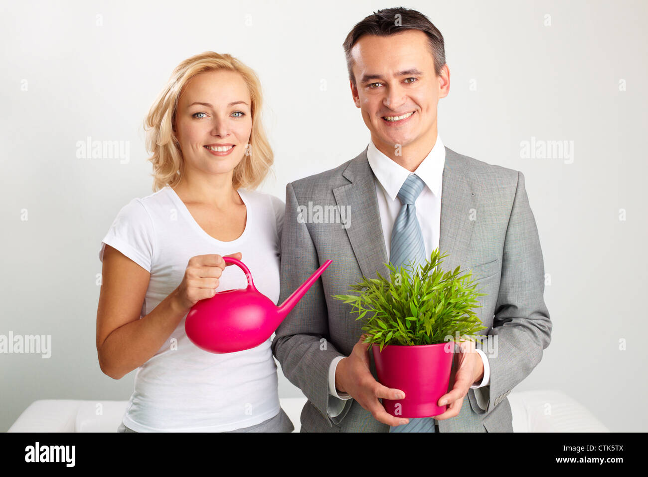 Portrait of happy gardeners holding a watering-pot and a plant Stock ...