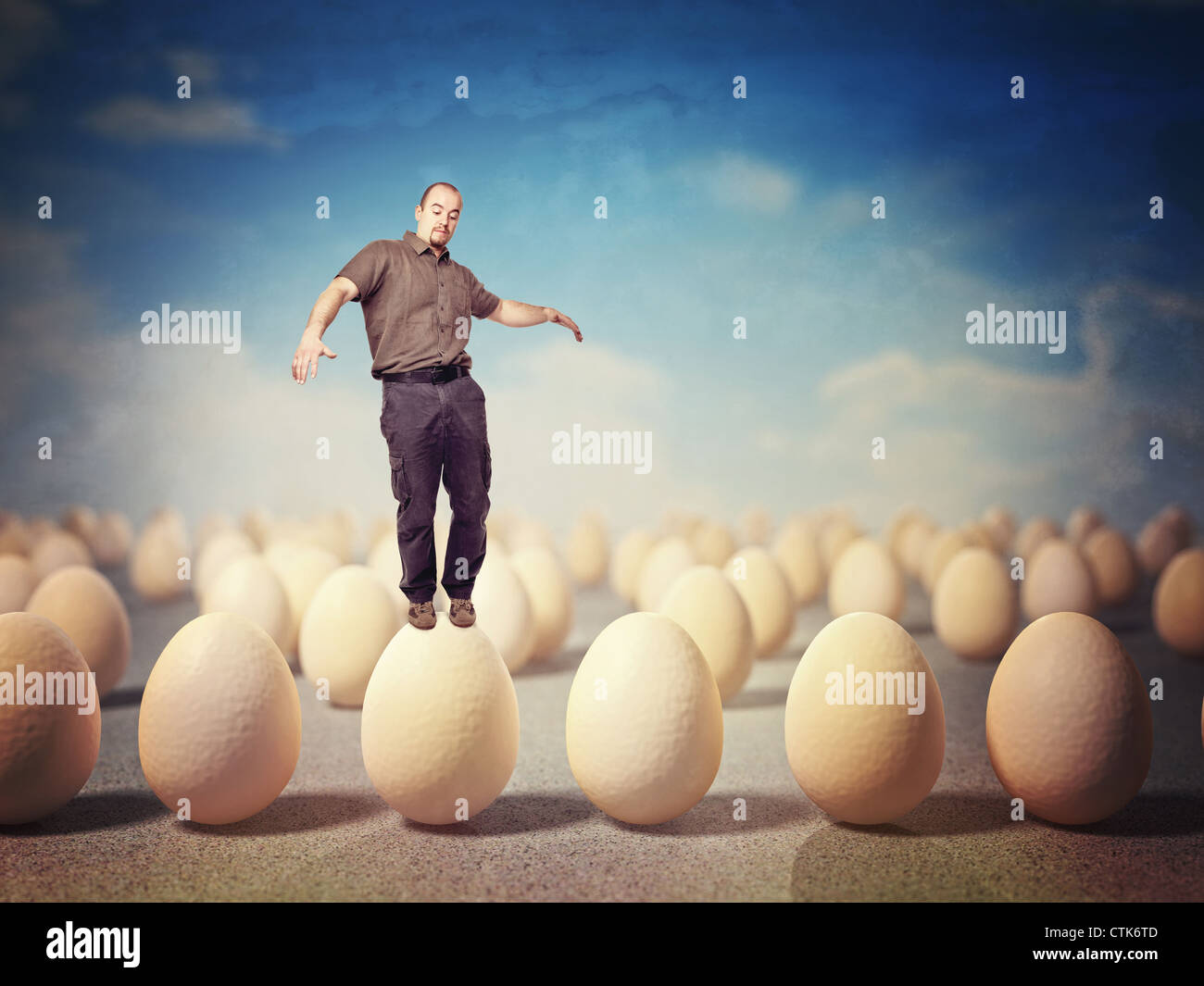 man try to balance himself on huge 3d eggs Stock Photo