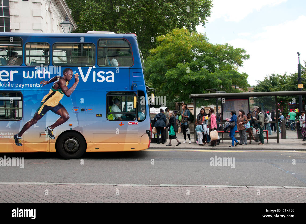 Narrow Way bus stop Hackney. Advert for Visa card featuring Usain Bolt, next to queue of people waiting for bus. Stock Photo