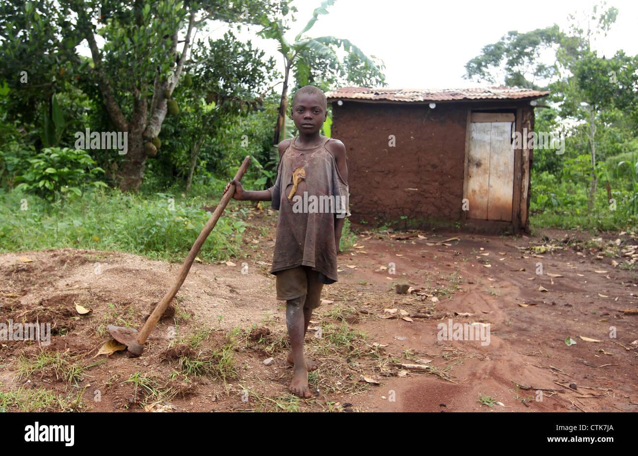 A young boy pictured outside his family home and small plot of land in the Mawale area of the Luwero district in central Uganda. Stock Photo