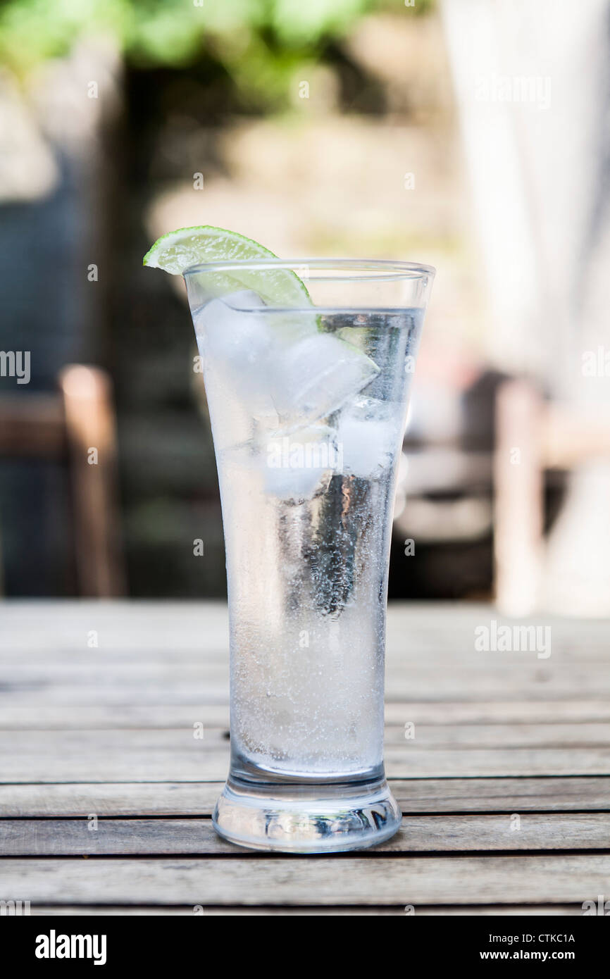 Glass of sparkling mineral water with ice and lime on a table on a