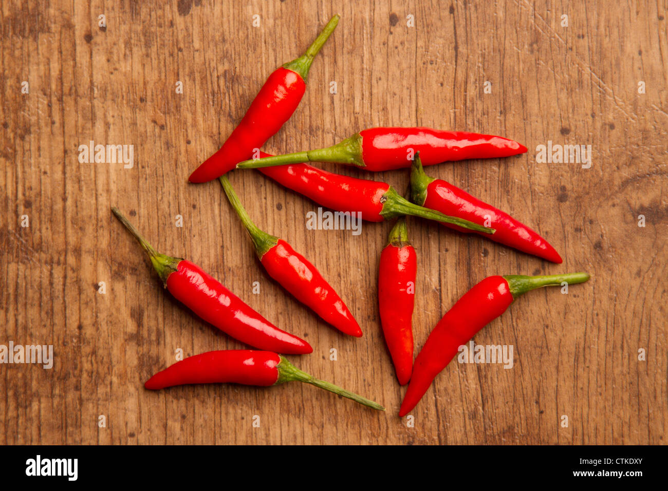 A handful of red chillis placed on a wooden floor Stock Photo