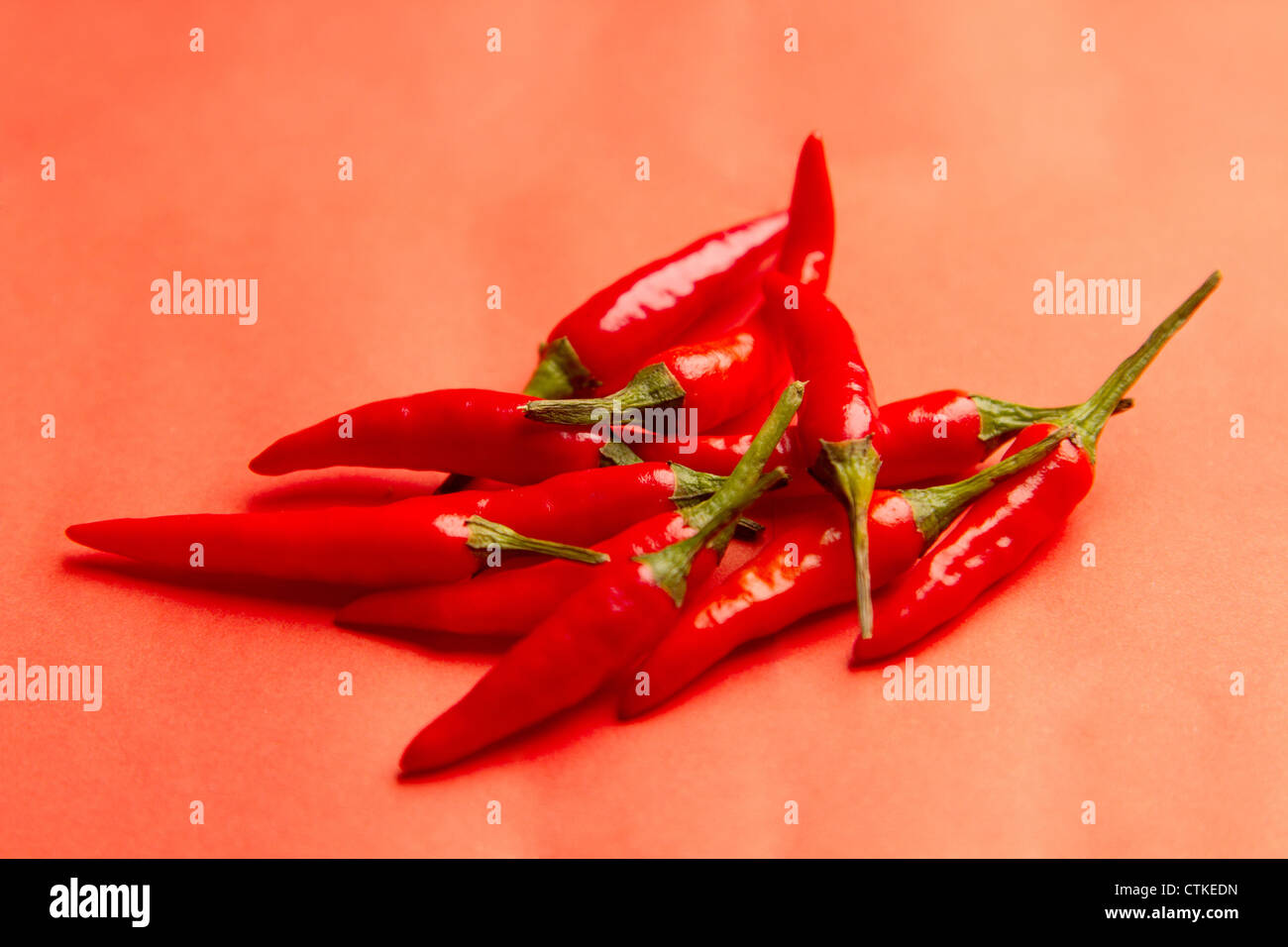 A handful of red chillis on a bright red background Stock Photo