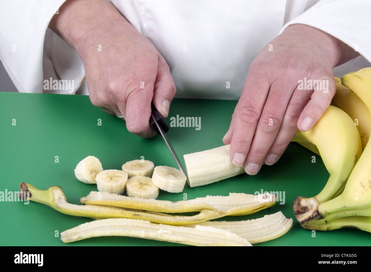 female chef cutting a banana with a kitchen knife Stock Photo Alamy