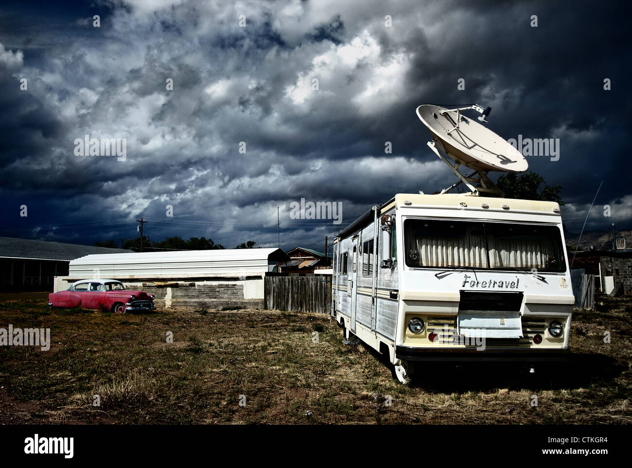 old camper with giant satellite dish on the roof against a stormy sky