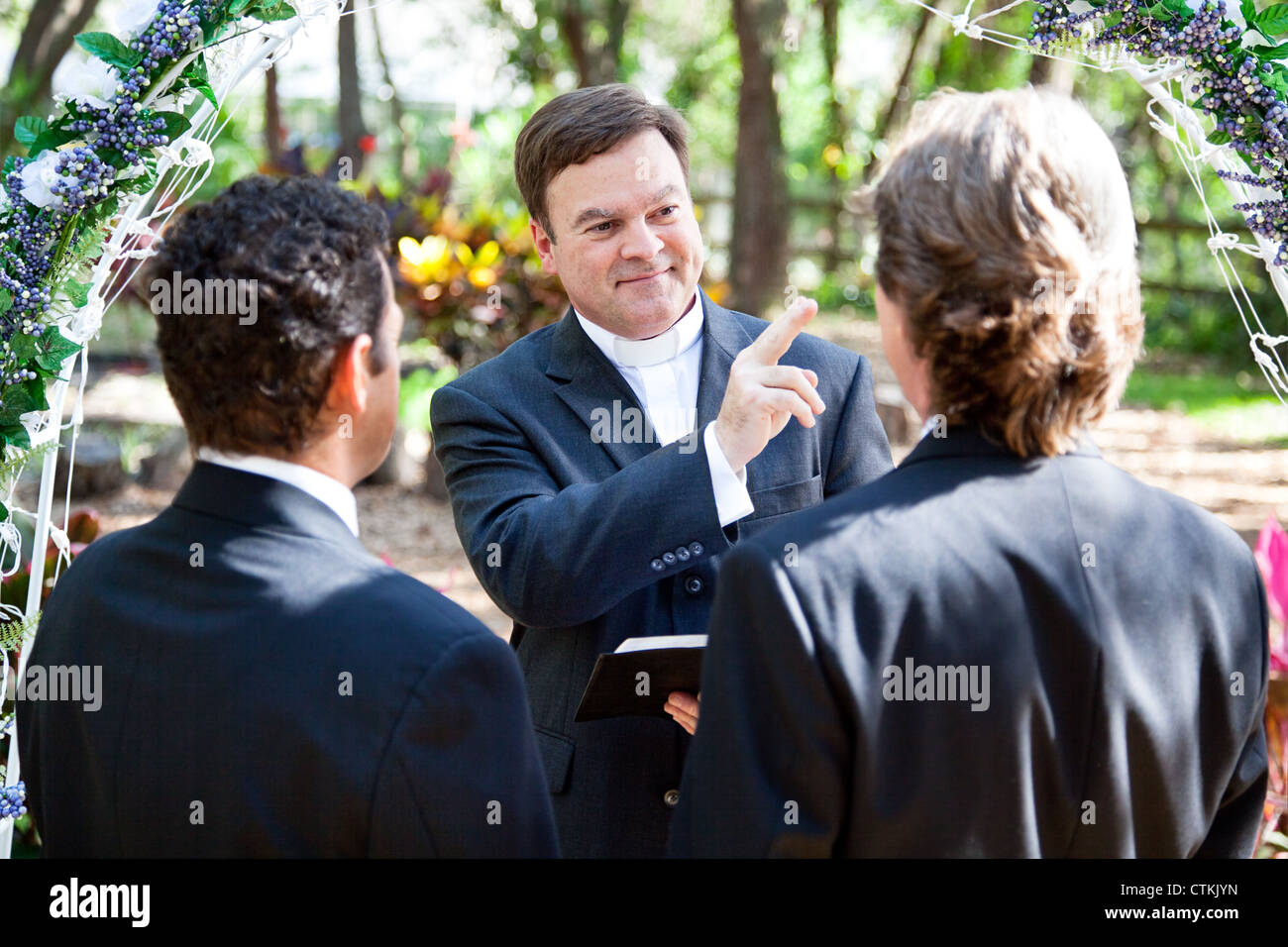 Minister blessing a gay couple while performing their wedding ceremony.  Stock Photo