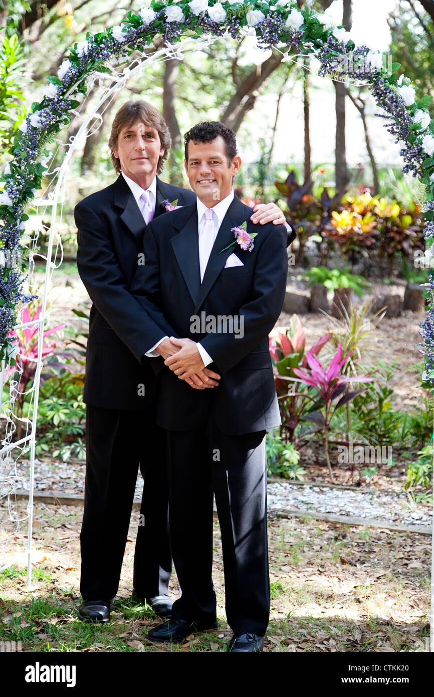 Newly married gay couple posing for a portrait under the wedding arch.  Stock Photo