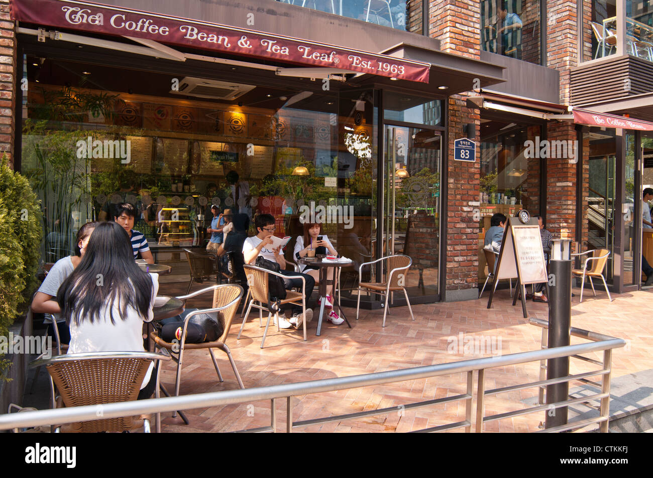 Young Koreans reading and talking in a pavement cafe, Seoul, Korea Stock Photo
