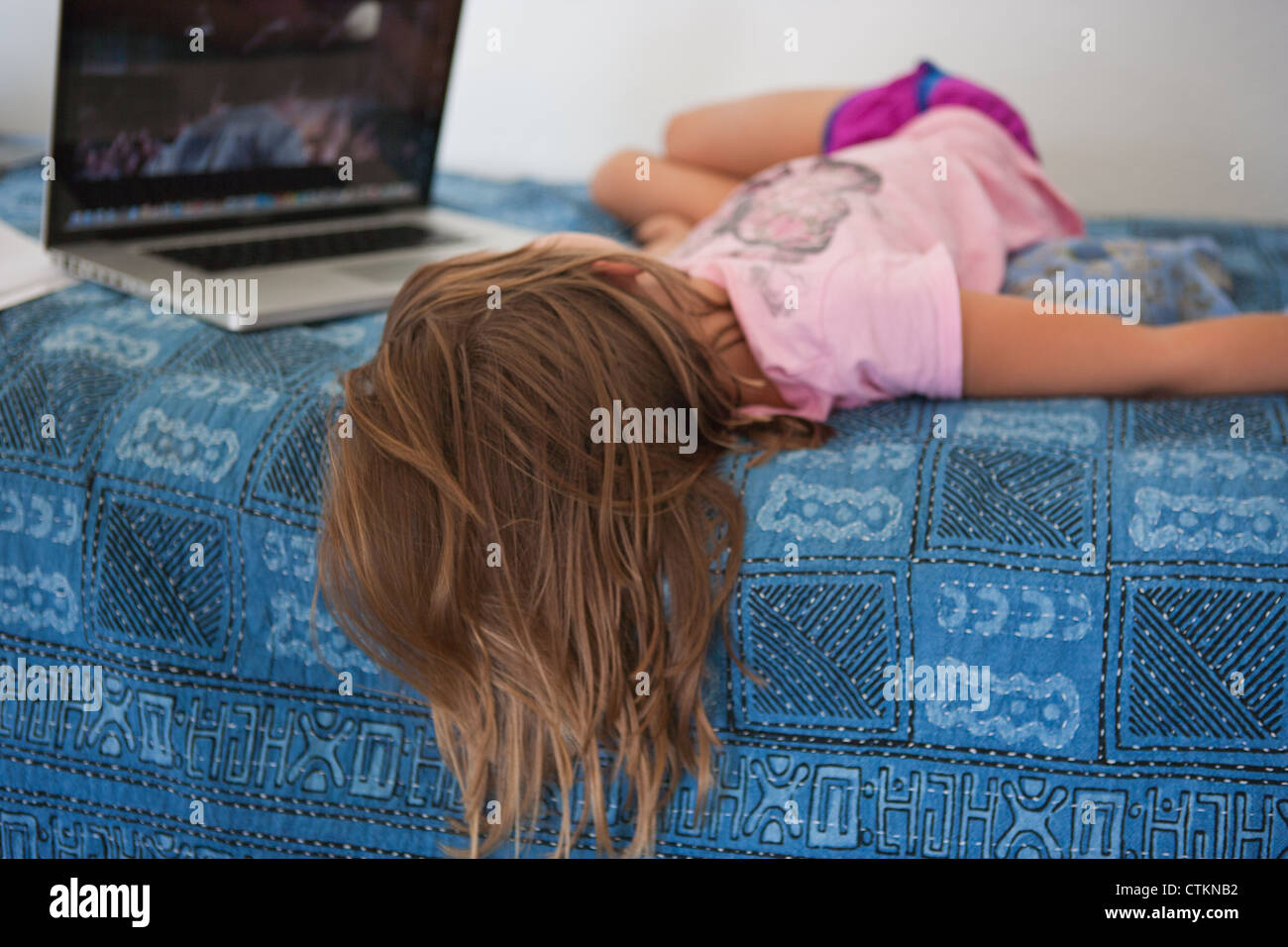 Life In A Year En Streaming Seven year old girl laying in bed watching a movie on a laptop Stock