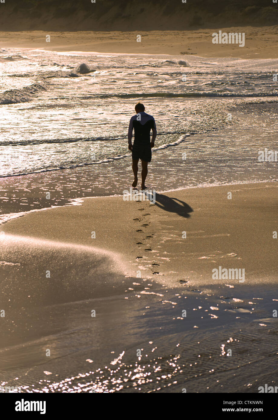 A man walking across the sand at Margaret River at sunset Stock Photo