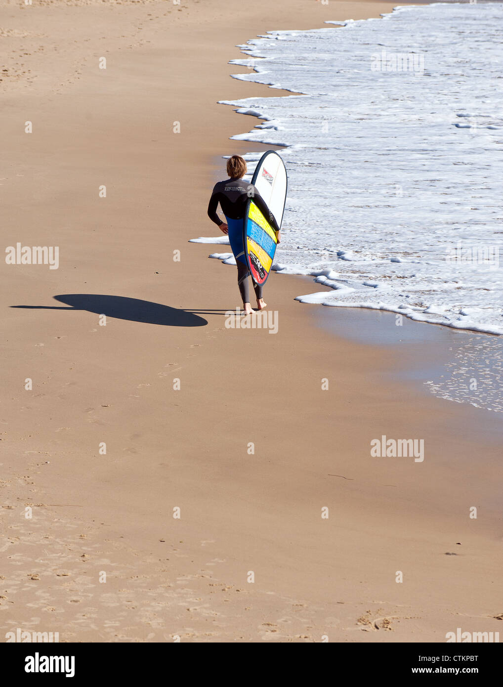 A young surfer carrying his surfboard across the beach at Alexandra Headland in Queensland Stock Photo