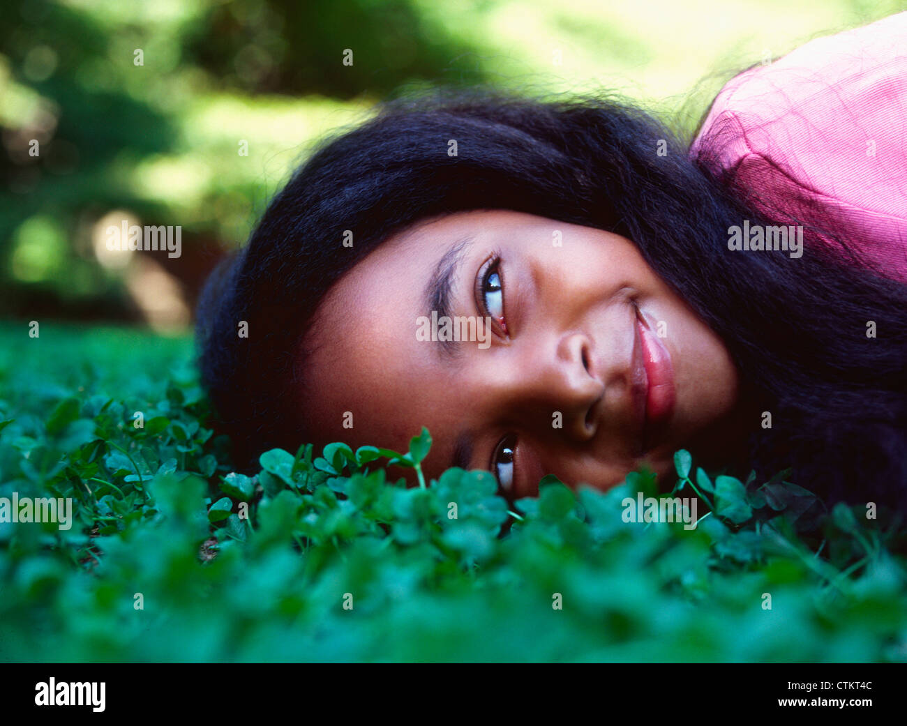 A little girl (5-10 years old) laying down in a bed of clover. Stock Photo