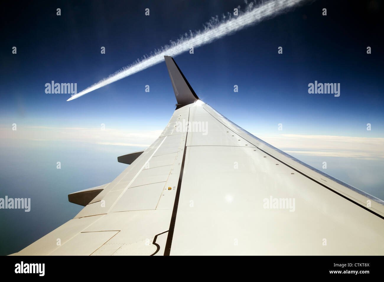 Dramatic airplane vapour trail passing a plane wing seen from inside the aeroplane Stock Photo