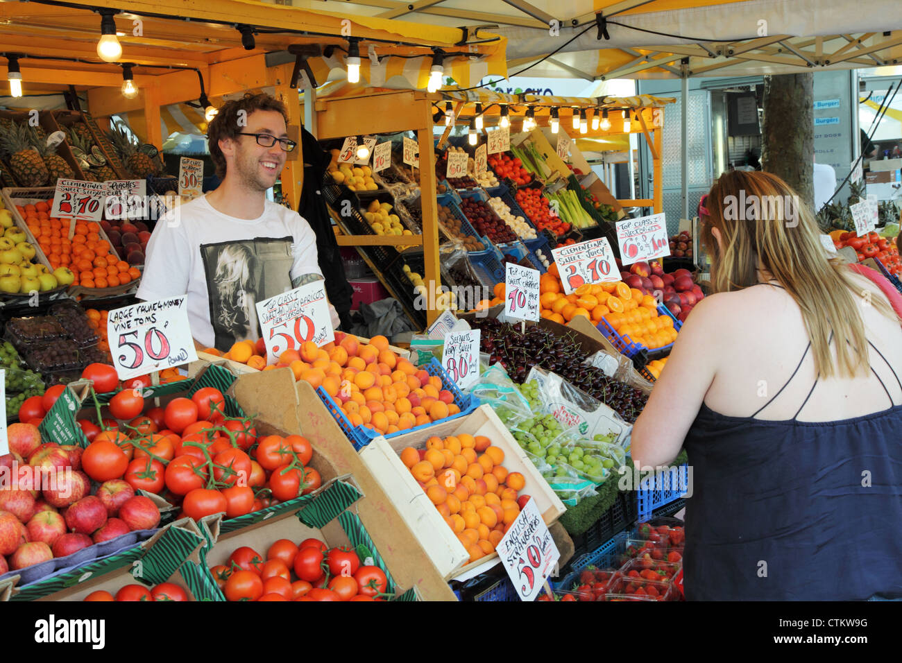 Smiling fruit and veg stall holder within Commercial Road street market