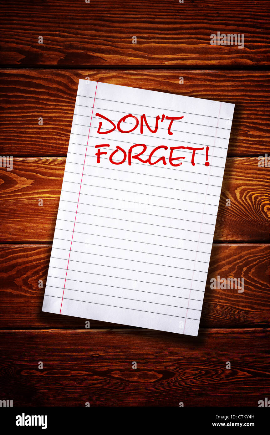 Don't forget, handwritten reminder paper note over a wooden background ...