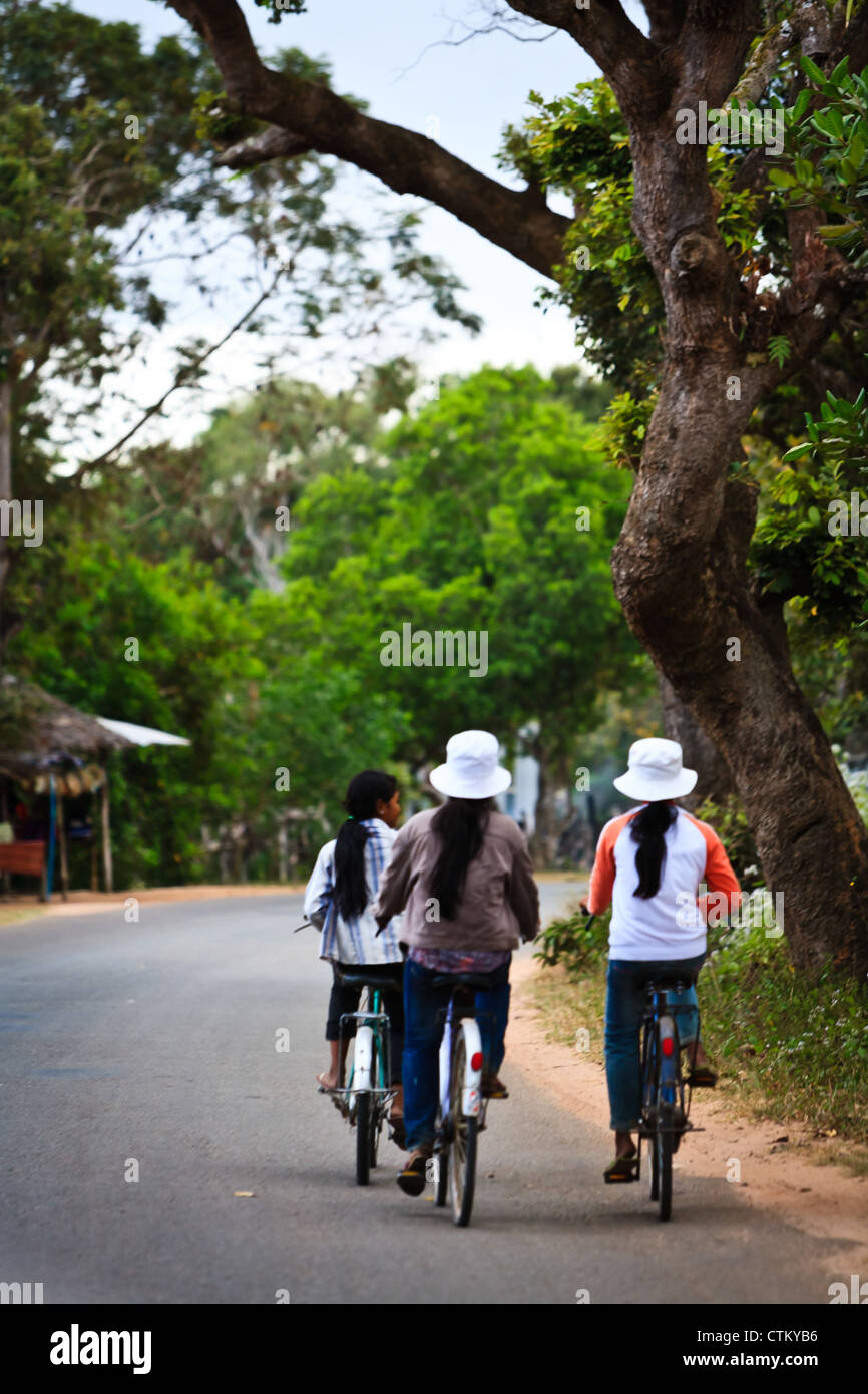 Group of local Cambodian women bike home from work, in Angkor Wat, a UNESCO World Heritage Site in Siem Reap, Cambodia. Stock Photo