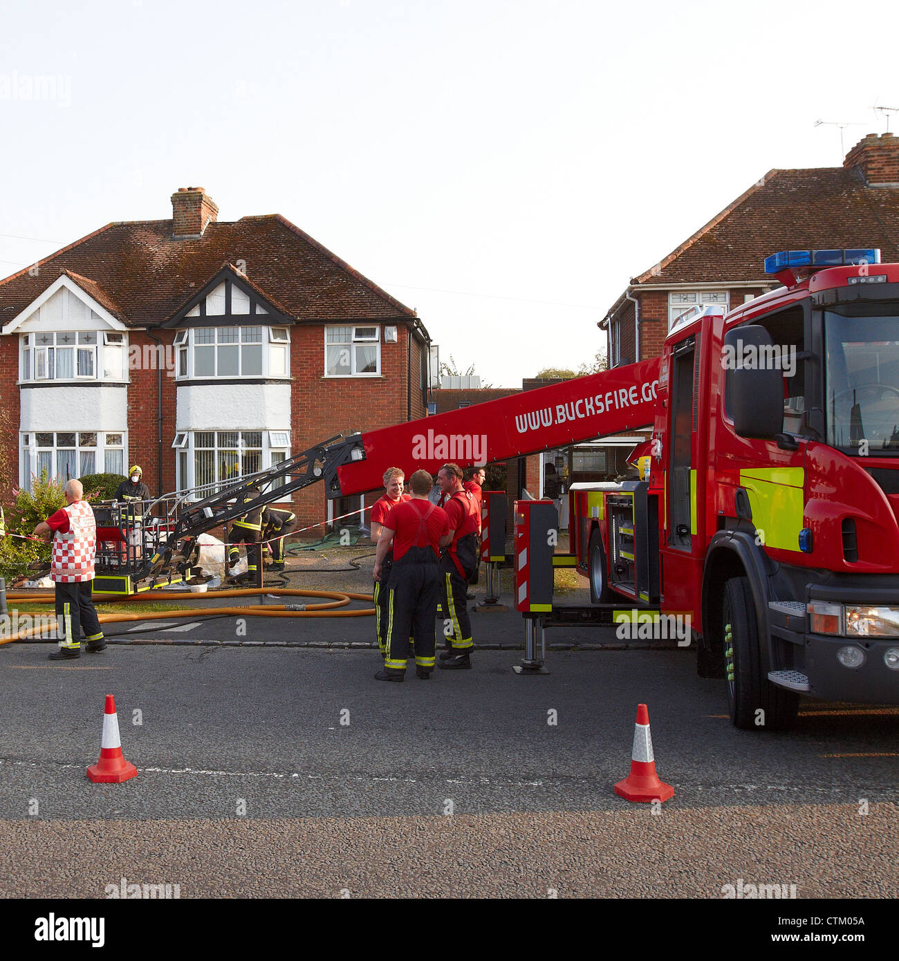 Fire fighters clean up after a house fire in Aylesbury, Buckinghamshire
