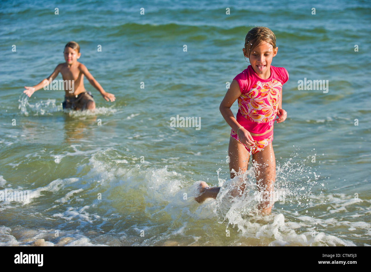 Two kids play in ocean waves Stock Photo Alamy