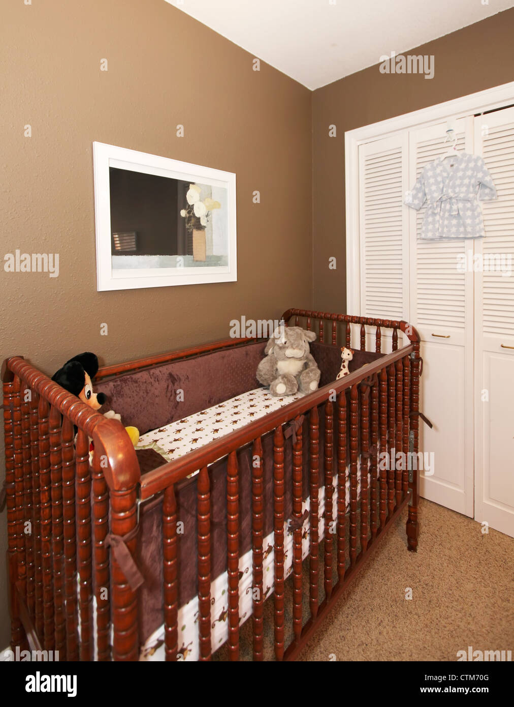 Cherry wood baby crib in nursery interior with brown wall Stock Photo