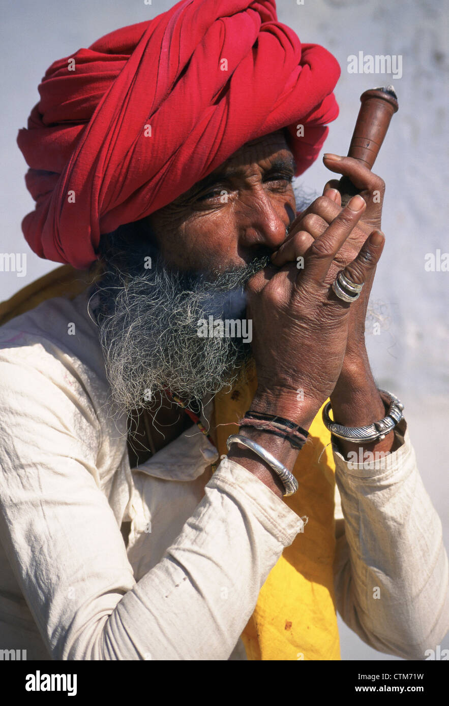 Indian man traditionally dressed smoking opium with his pipe. Stock Photo