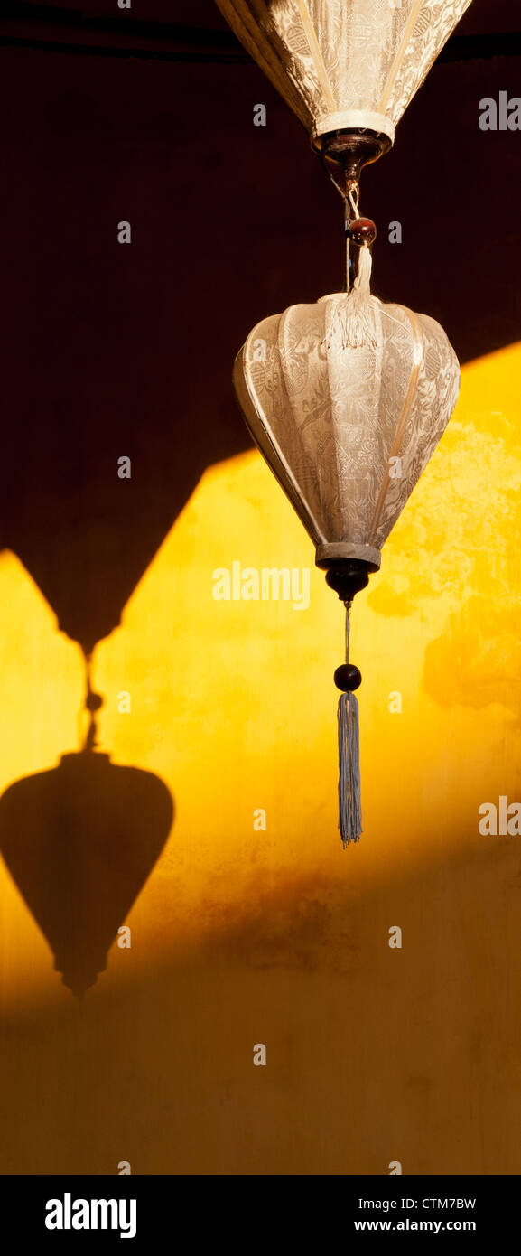 Two cream ivory colored silk lanterns on an ochre wall, Hoi An, Viet Nam Stock Photo