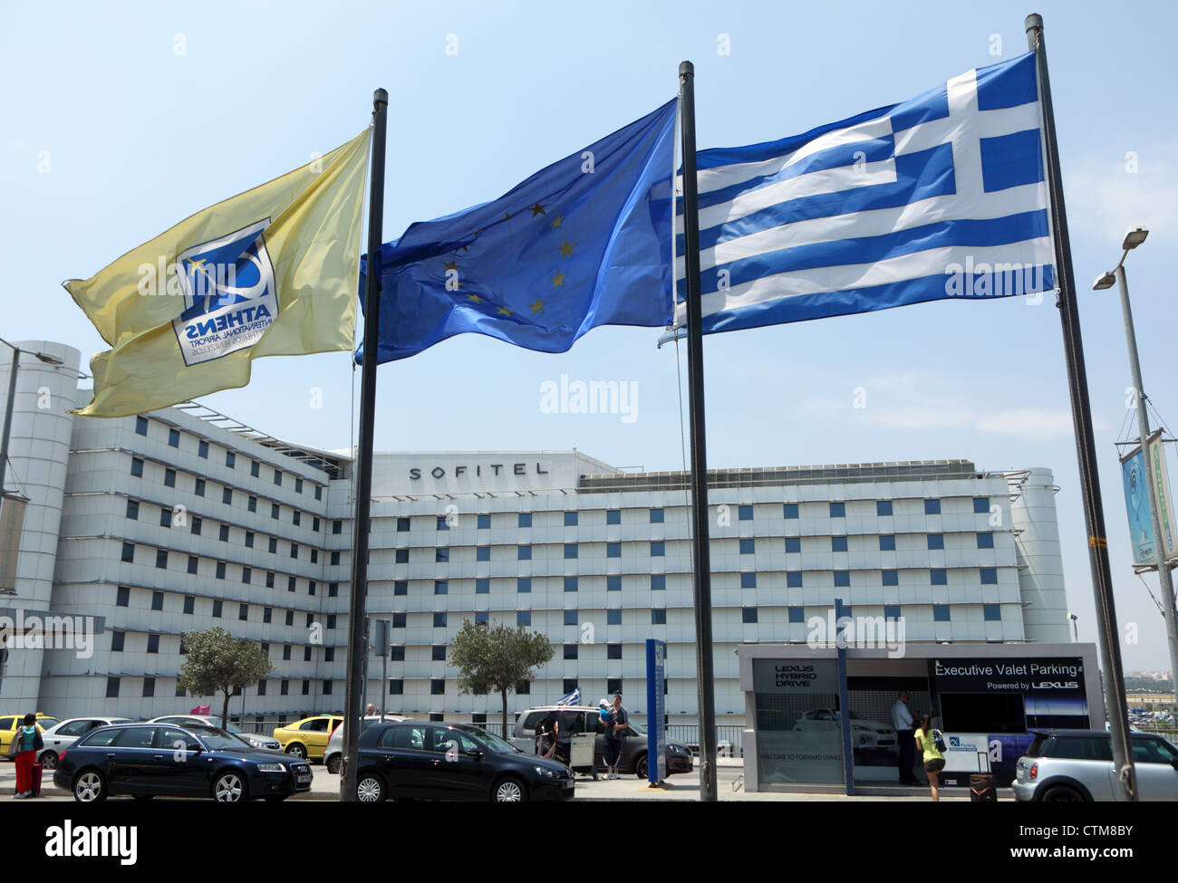 Flags of Greece the EU and Athens airport flying outside the arrival terminal, with the Sofitel hotel in the background Stock Photo