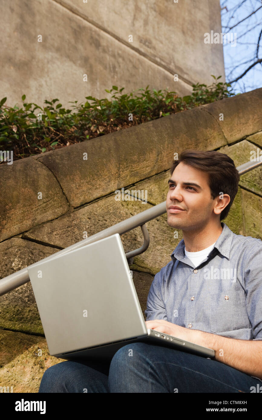 Thoughtful young man using laptop outdoors Stock Photo