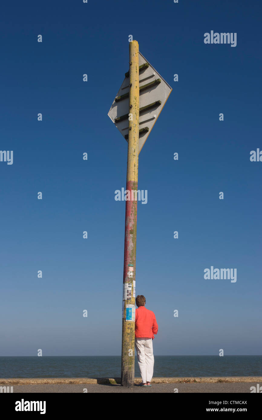 person stands below a maritime shipping transit navigation sign at the ...