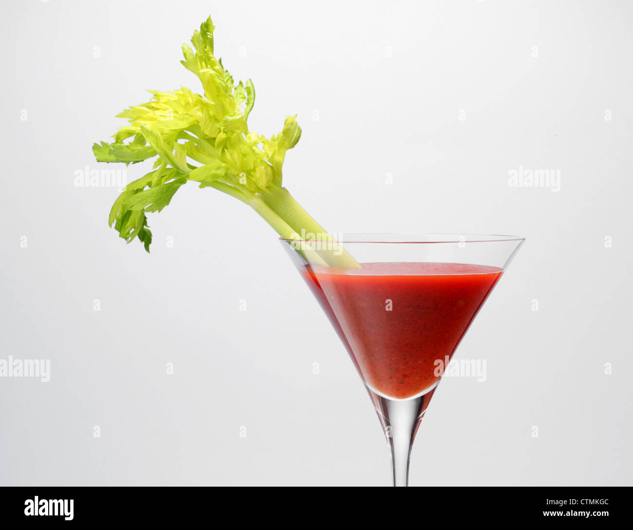 A  red vegetable juice in a stemmed glass with vegetable garnish. Celery stalk Stock Photo