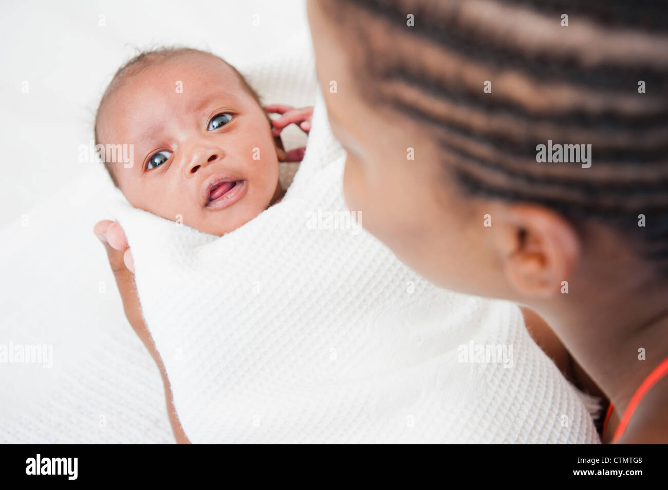 Over the shoulder view of newborn baby wrapped in blanket by his mother
