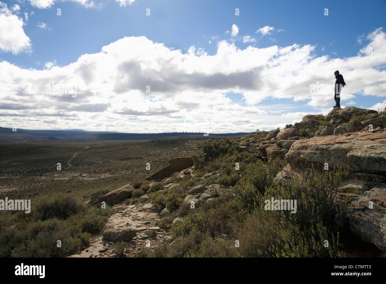 A teenage boy stands on a hill side, Great Karoo, South Africa Stock Photo