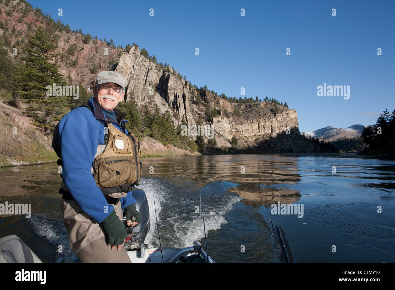 Fisherman pilots his jet boat past steep cliffs along the Missouri