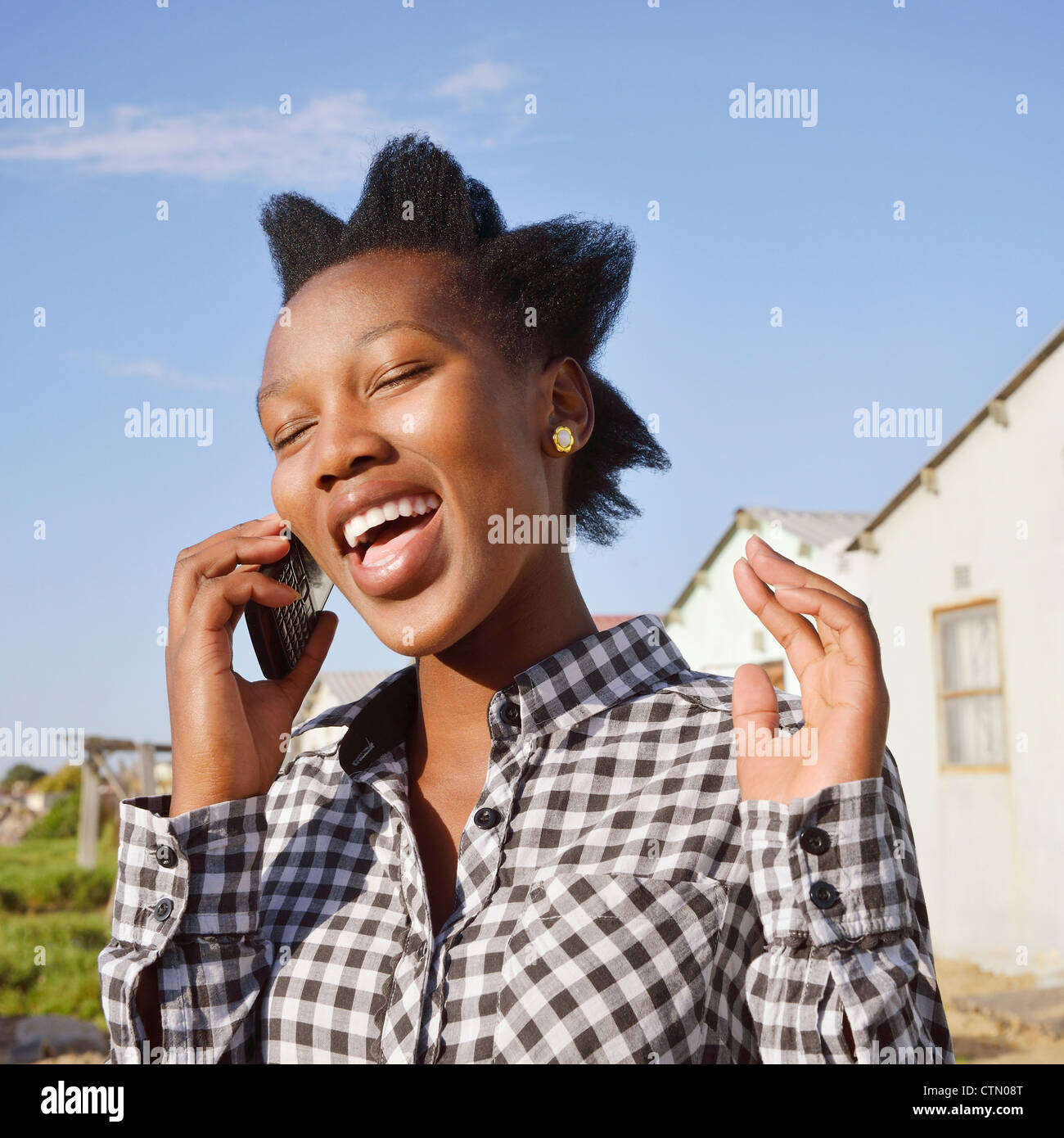 Woman with spiky hair chatting on a mobile phone, Gugulethu, Cape Town Stock Photo