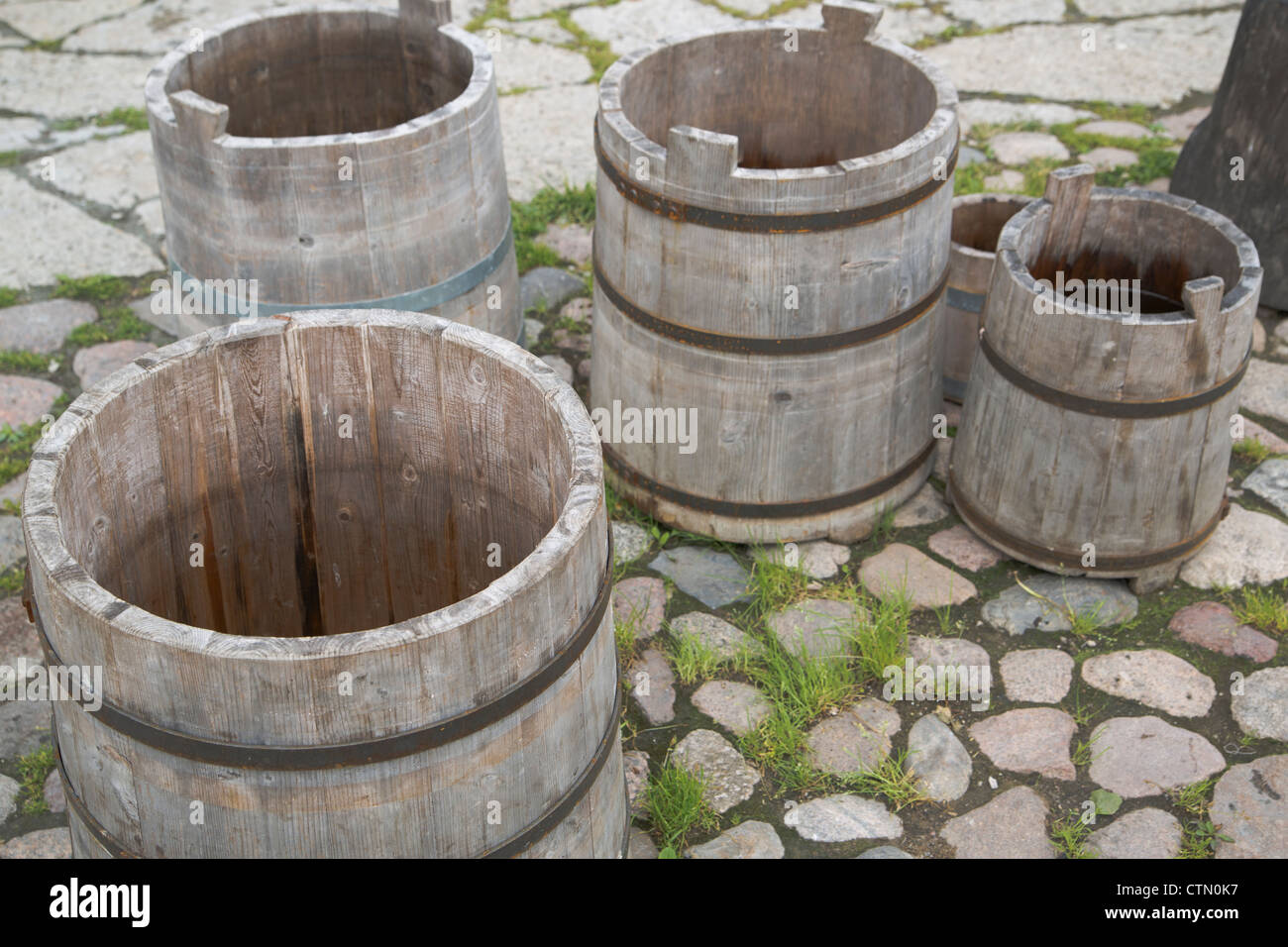 Four empty water barrels on stony yard floor Stock Photo Alamy