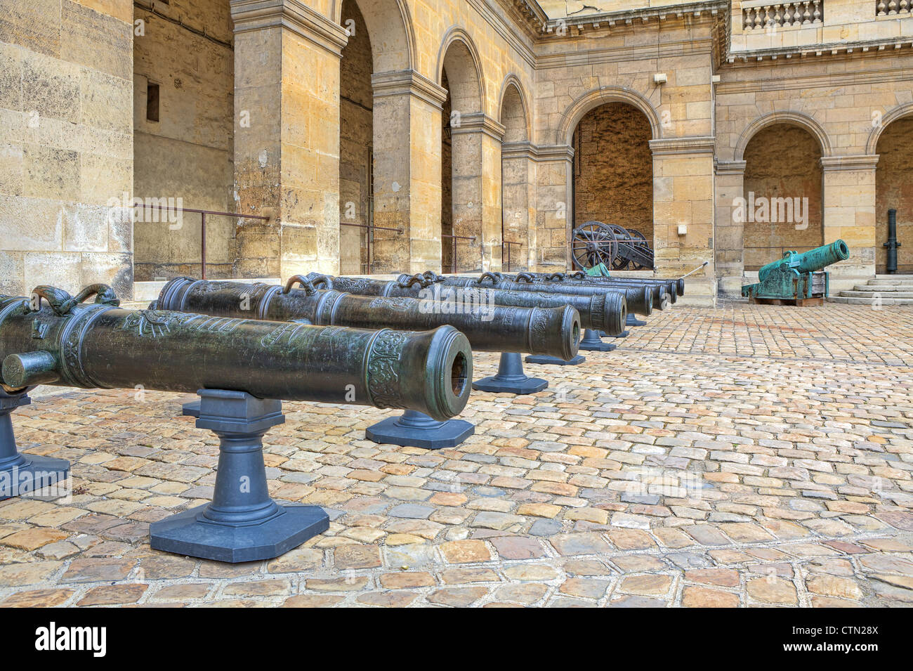 Ancient cannons stand in the row on cobbled yard in museum at Les Invalides in Paris, France. Stock Photo